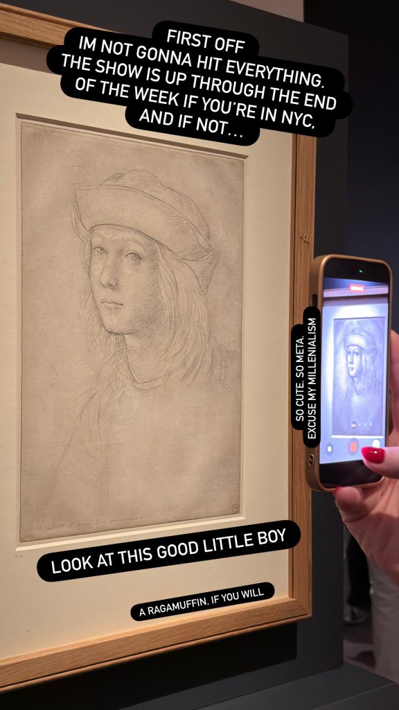 A delicate silverpoint drawing of a young person with soft features, long hair, and a beret-like cap, displayed in a wooden frame. A visitor photographs the work with a smartphone, the phone screen visible at right.