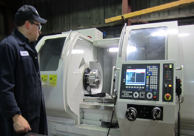 Machinist inspecting a CNC lathe.