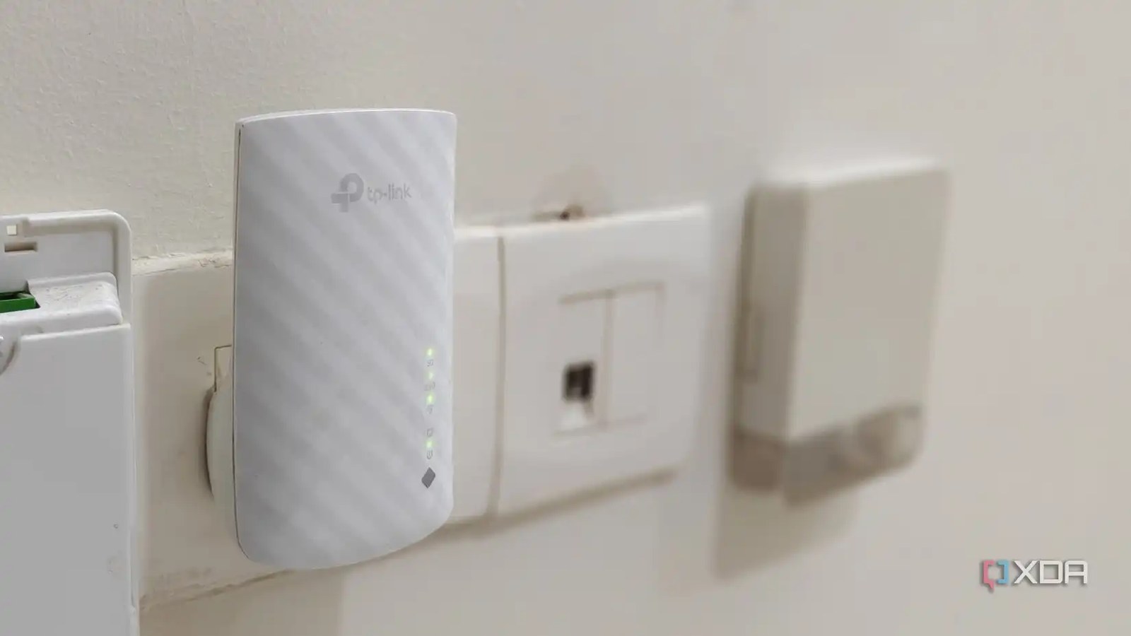 A white Wi-Fi extender plugged into a wall outlet