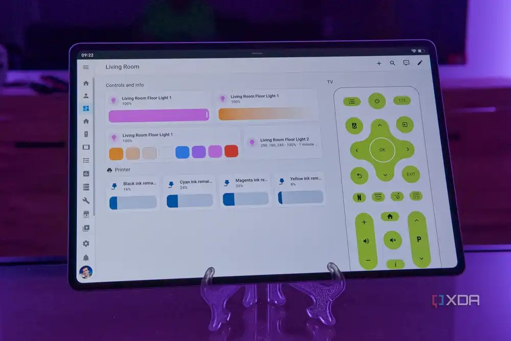 A tablet displaying a Home Assistant dashboard with lights, a printer, and a TV remote for the living room. The lights are set to lilac, which can be seen in the background