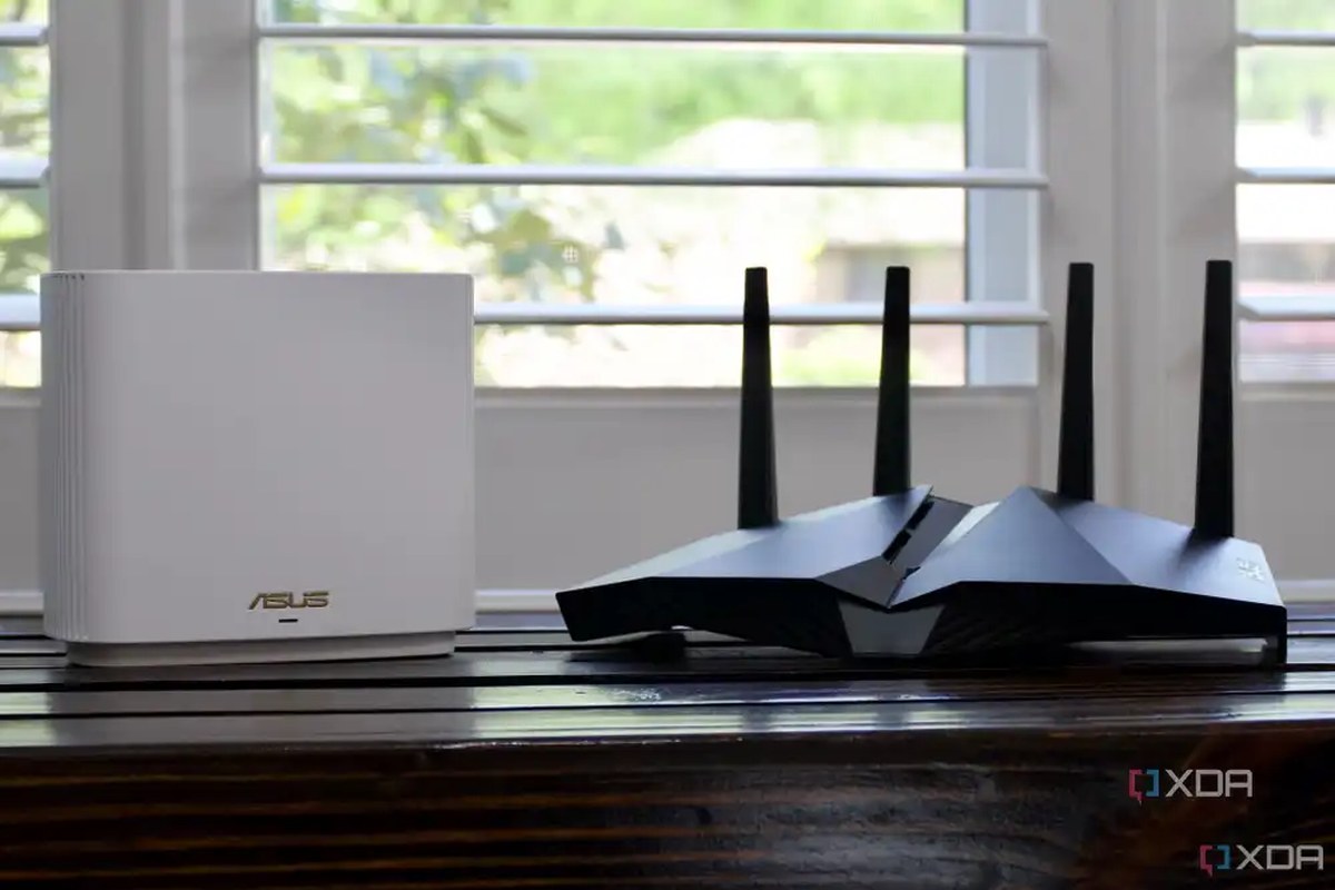 a plain white router with no visible antenna placed alongside a big gaming router