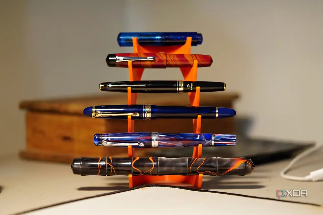 Six pens on a fountain pen stand with a blurry background