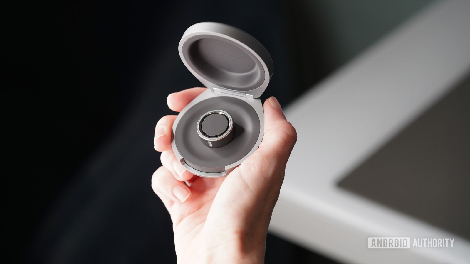 An Oura user holds an Oura Ring 4 Charging Casein hand.