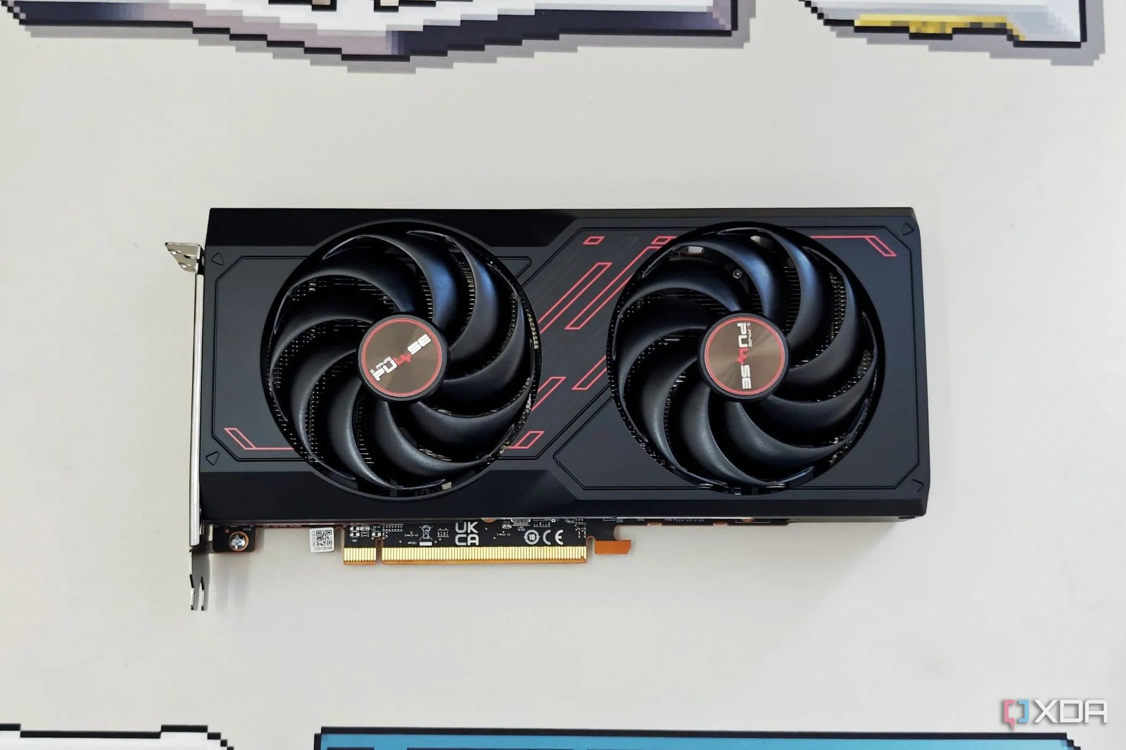 An image showing the Sapphire Radeon RX 7600 Pulse OC GPU kept on a beige deskmat.